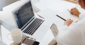 Host working through listing figures on a laptop and notepad