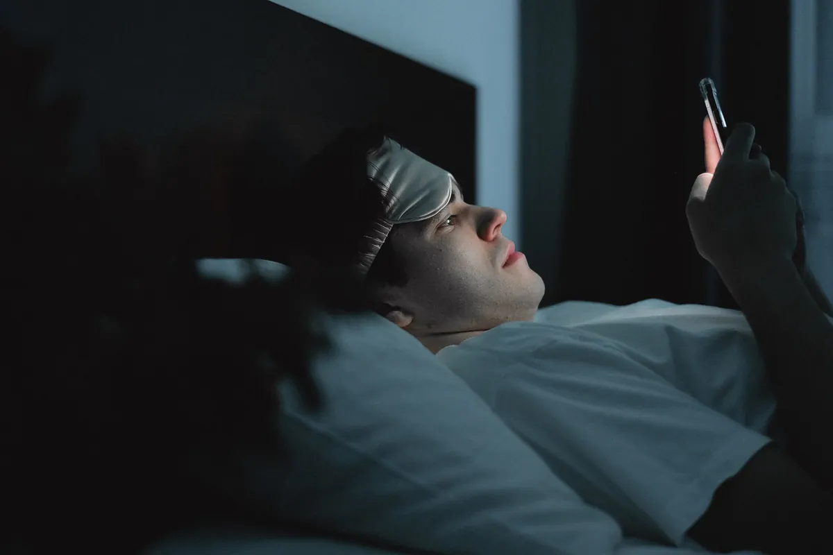 A host looking at a phone in the dark, late at night