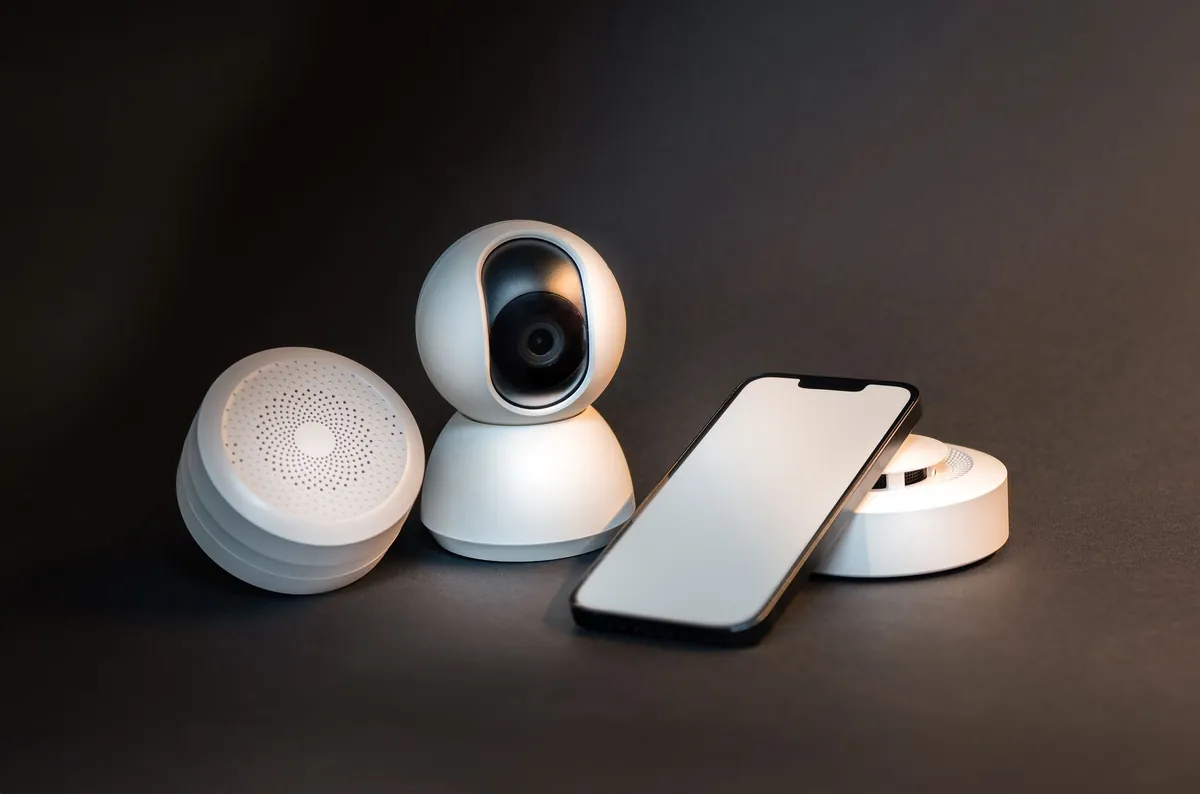 A small indoor camera and a phone on a dark surface