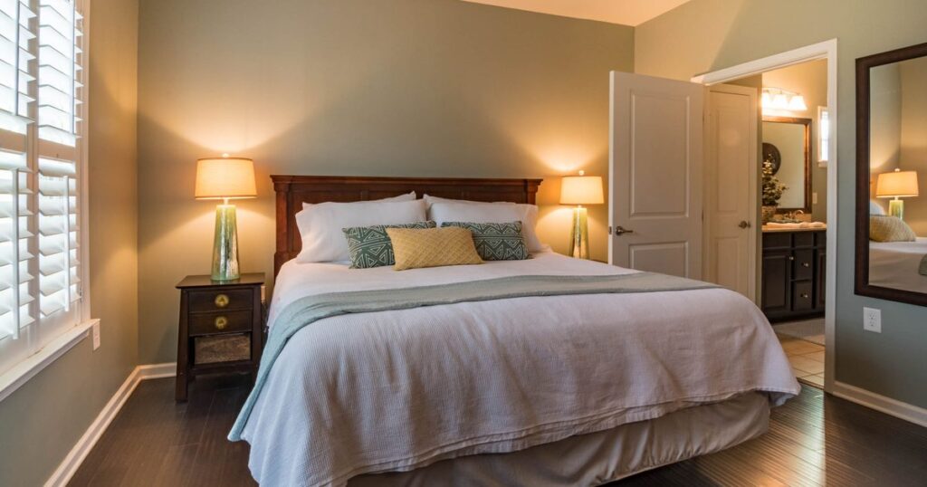 A made double bed with lamps on both sides in a warmly lit guest bedroom