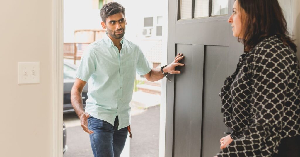 A guest at an open front door talking with the host