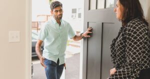 A guest at an open front door talking with the host