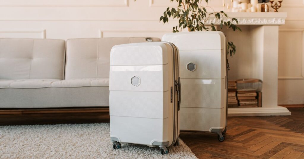 Two white hard-shell suitcases standing in a bright living room