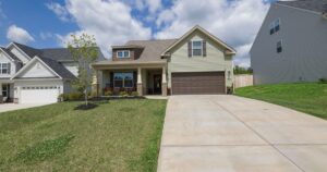 A two-storey suburban house with a long concrete driveway and a green lawn