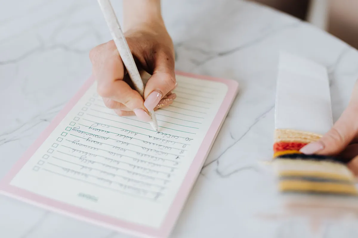A hand writing a checklist on a lined pad