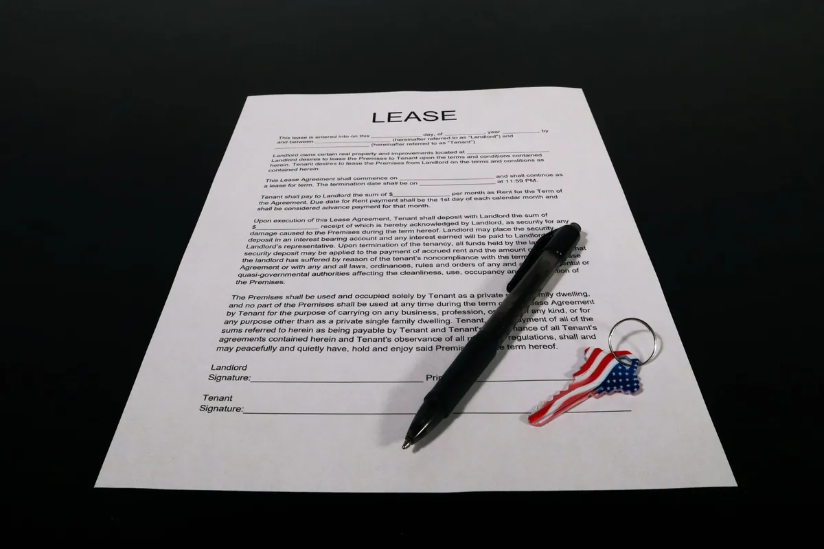 A printed lease document with a pen resting across it on a dark surface