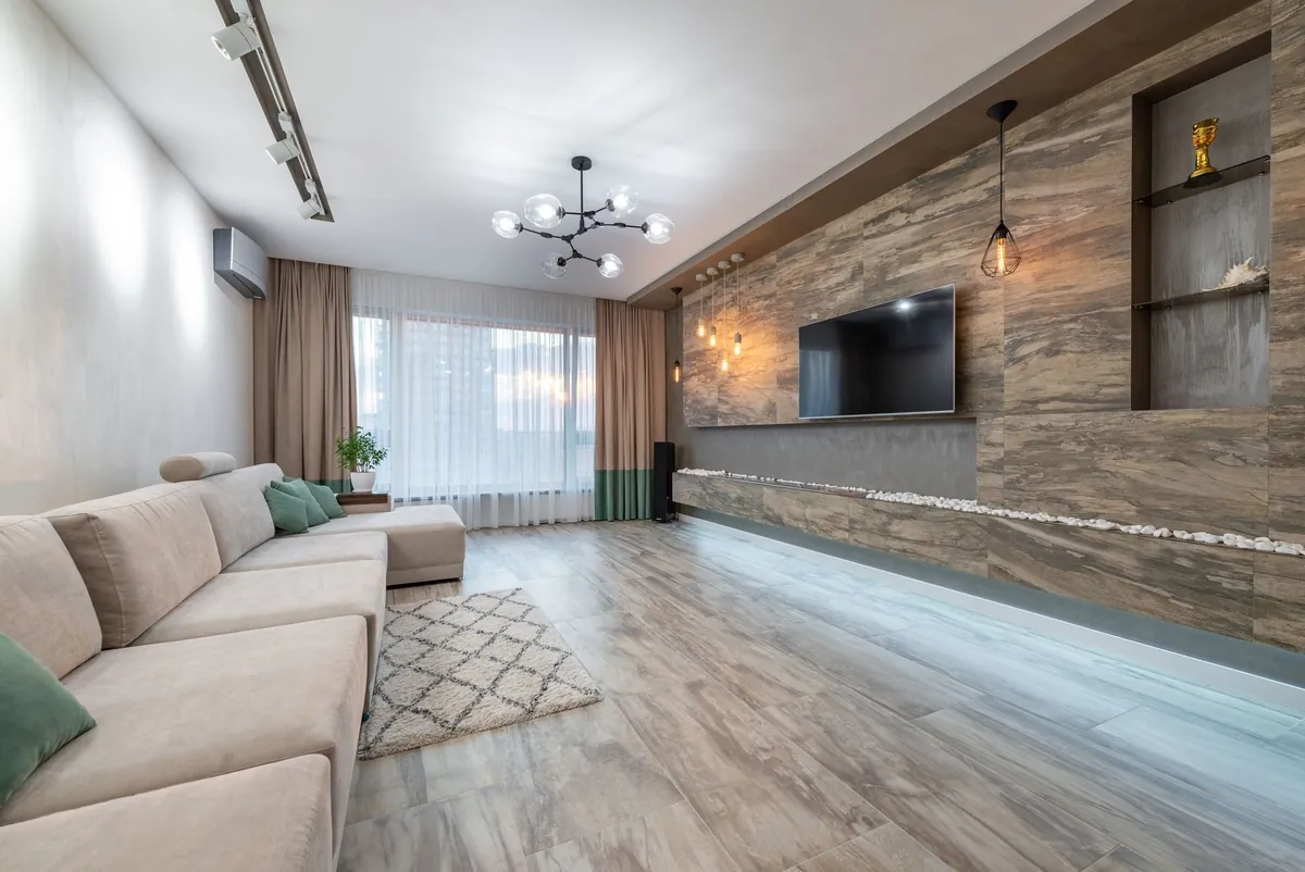 A furnished living room with a large sofa, wooden floor and warm lighting