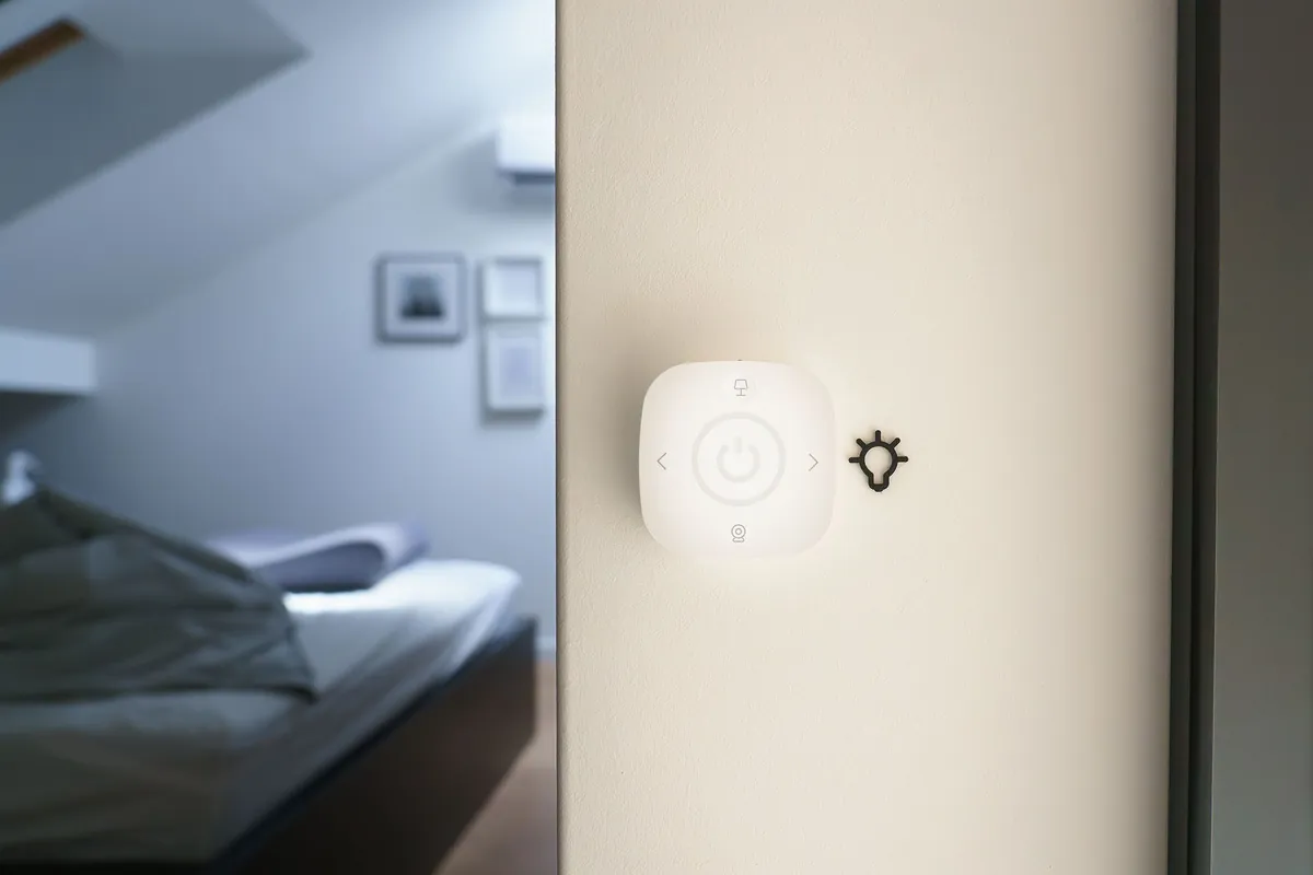 A minimalist bedroom with a small smart-home switch panel on the wall