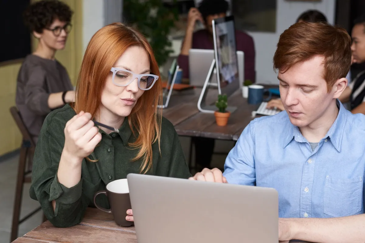 Two colleagues sitting side by side at a laptop in a bright office