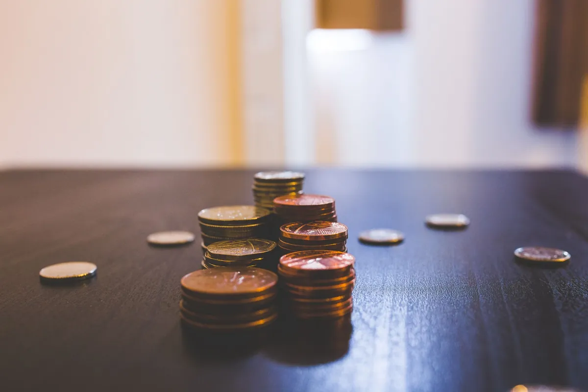 Coins stacked in uneven piles on a dark table