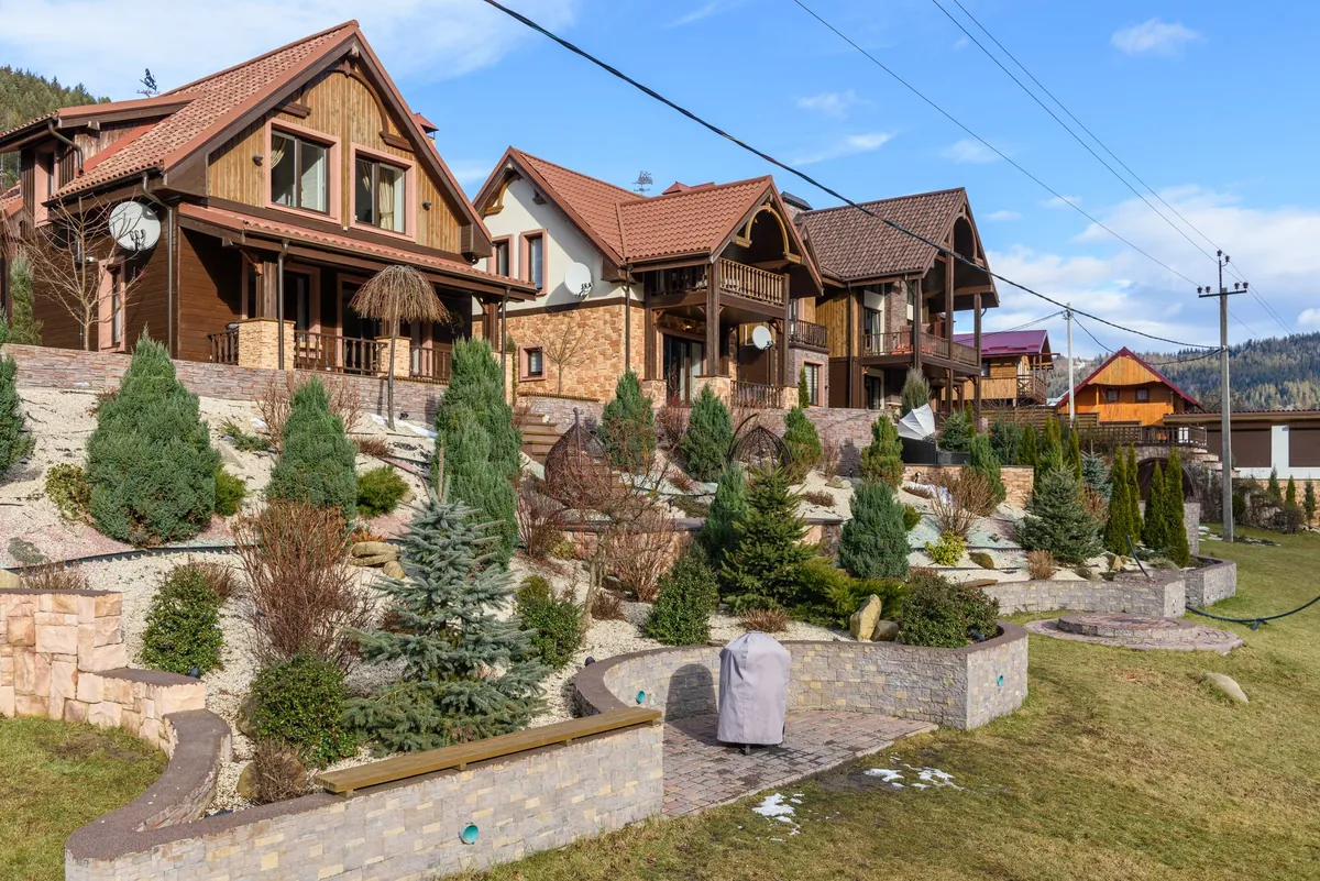 Several rustic houses with sloped roofs above landscaped gardens