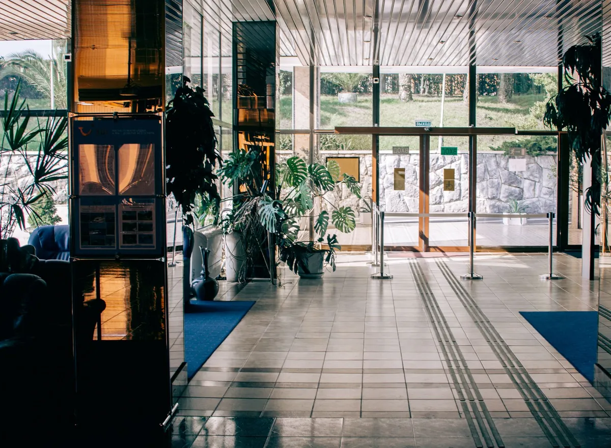 A modern lobby with a glass entrance and large potted plants