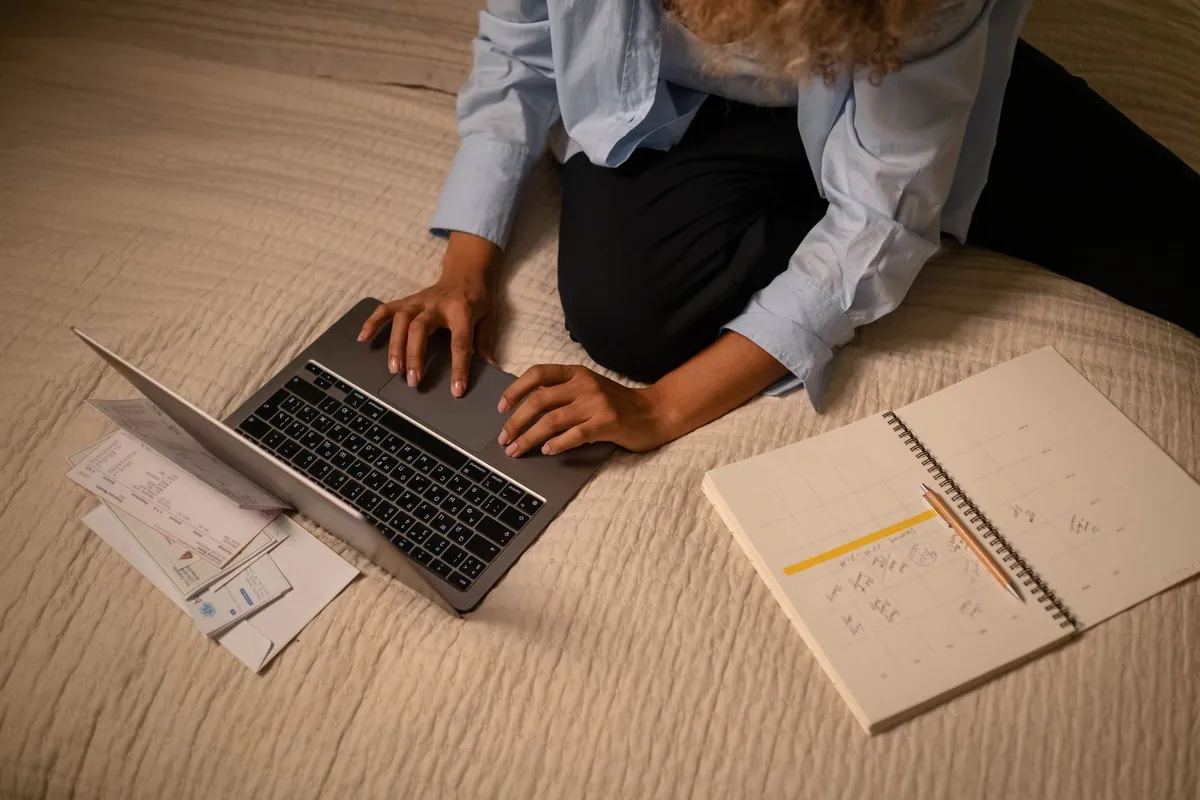 A woman sitting on the floor with a laptop and open notebooks, working through a plan