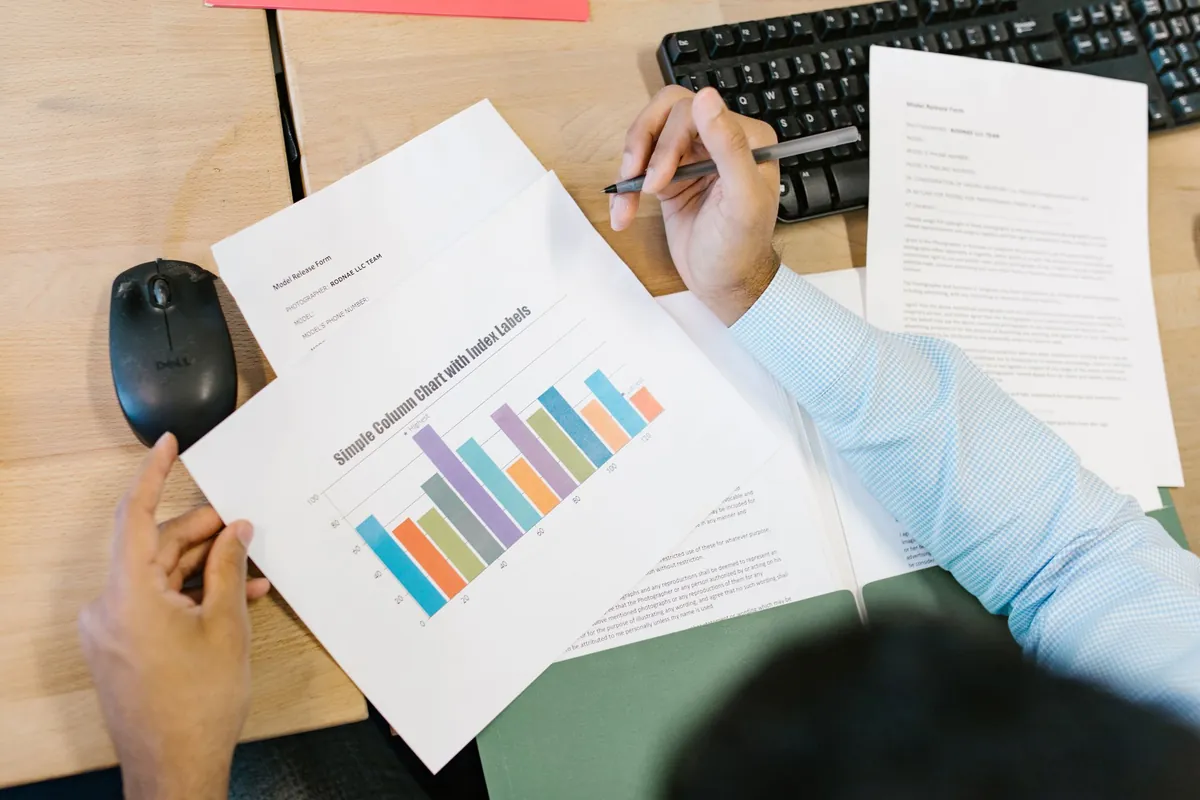 A person at a desk going through a printed bar chart with a pen