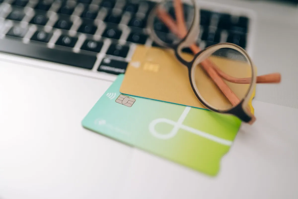Two payment cards and a pair of glasses lying on a laptop keyboard