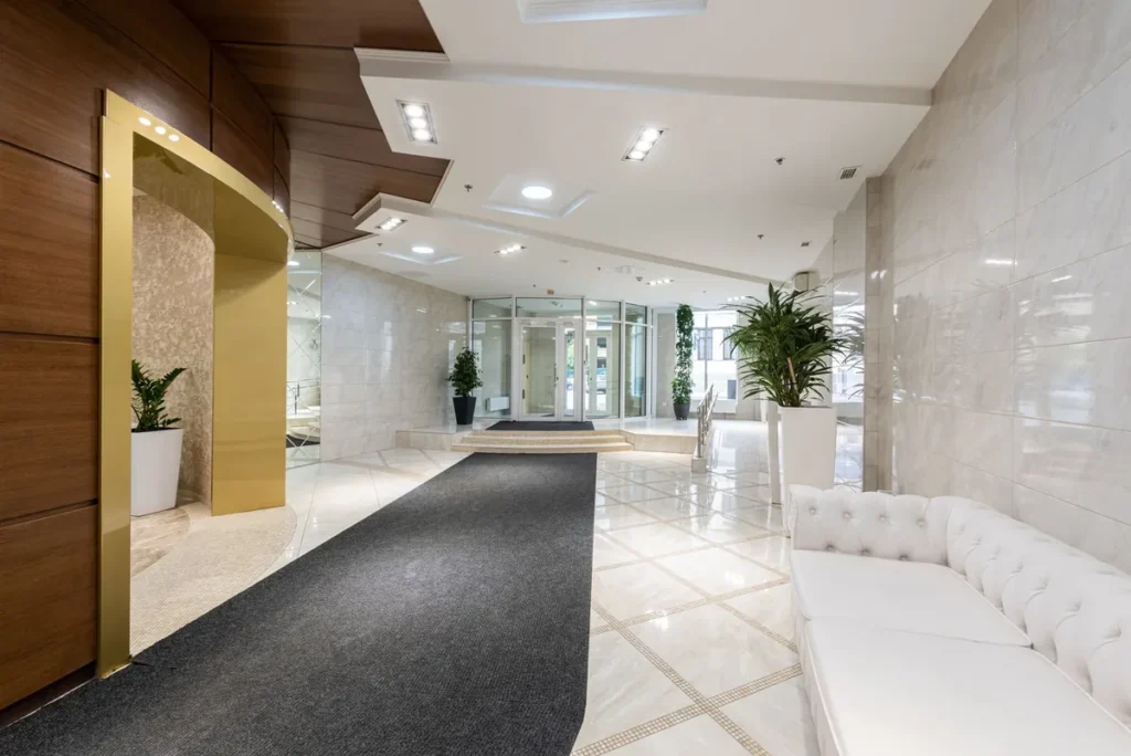 A contemporary hotel lobby, empty, with white seating and a long reception counter