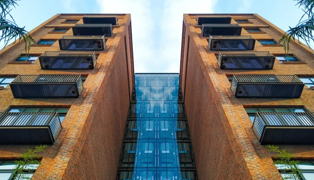 Two brick-and-glass wings of a modern building seen from directly below