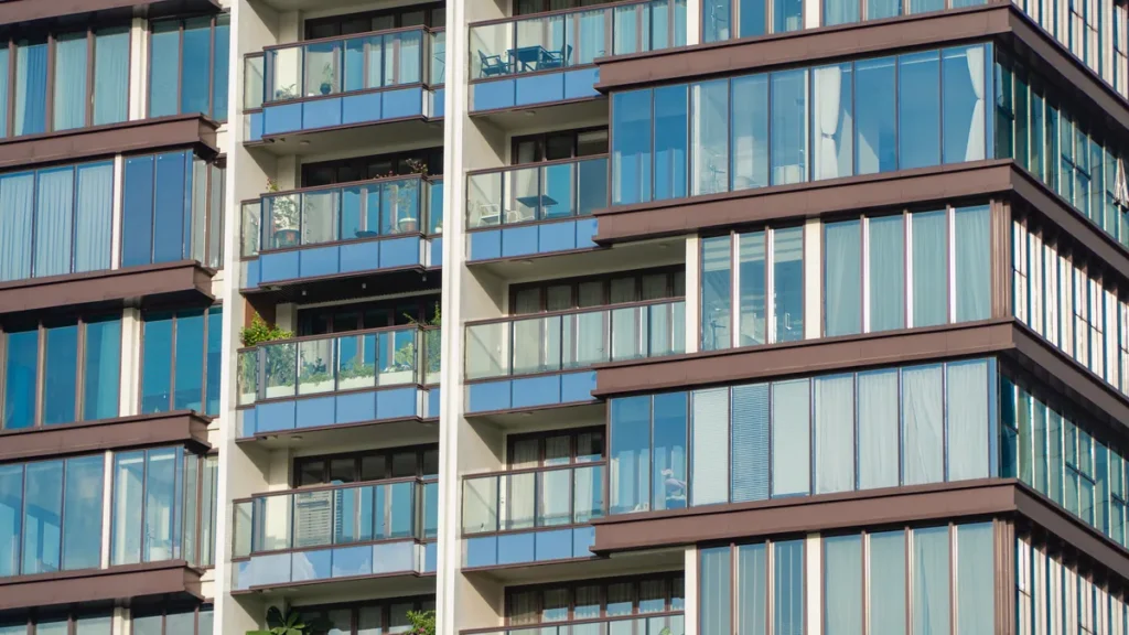 The blue-glass corner of a modern apartment building, balcony above balcony