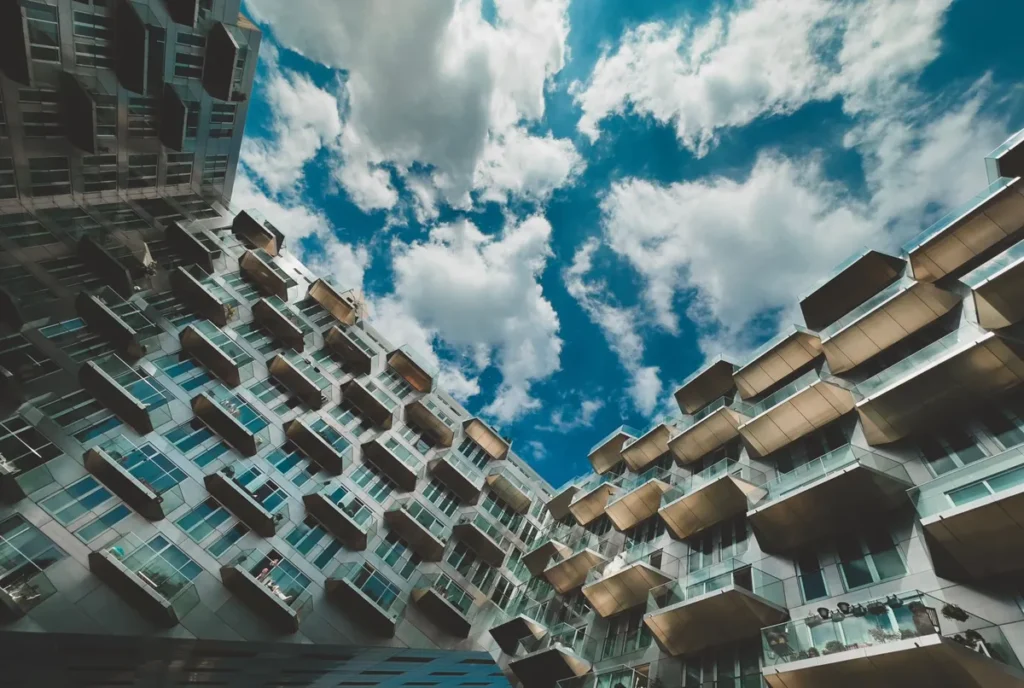 A low-angle view of a modern residential block, its balconies stepping up against a cloudy sky