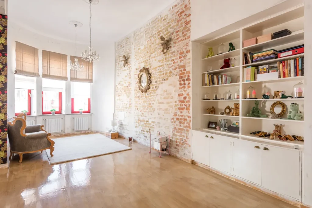 A bright loft interior with exposed brick, built-in shelving and tall windows
