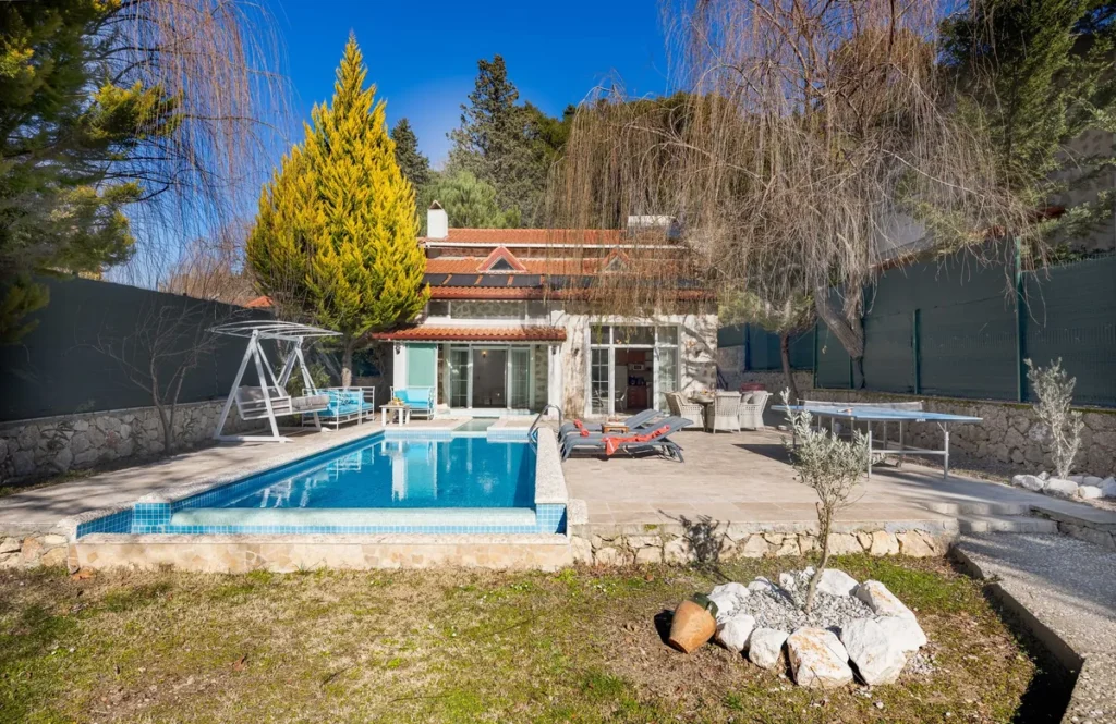 A villa with a swimming pool and sunbeds laid out on the terrace