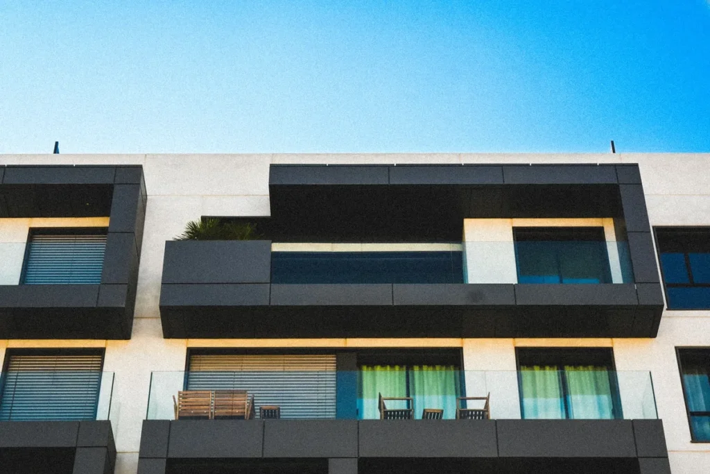 A minimalist apartment facade in black and cream, balconies against a clear sky