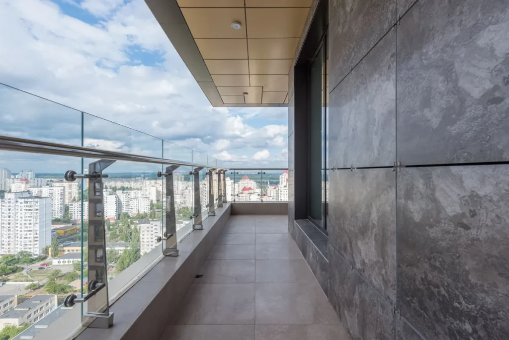 A long balcony with a glass balustrade looking out over a city