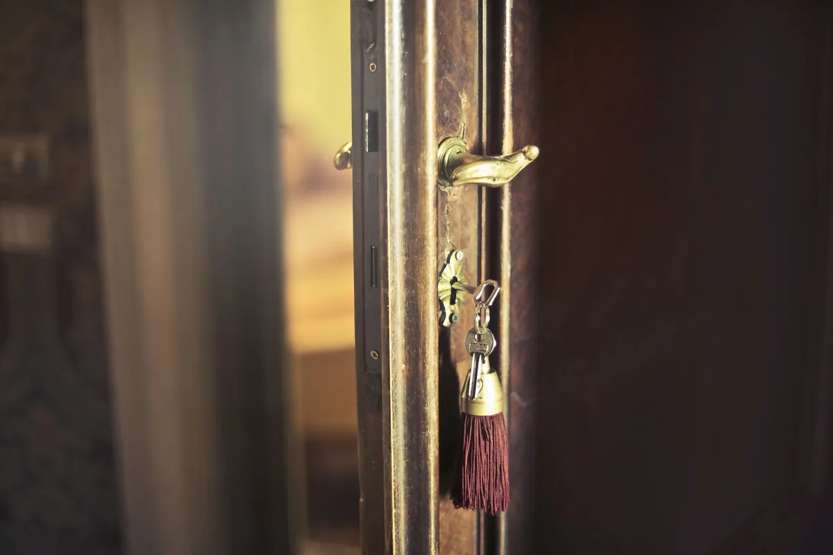 A key with a red tassel left in the lock of an open wooden door