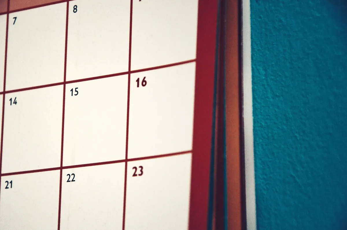 A blank monthly calendar grid on a wall, printed in red and white