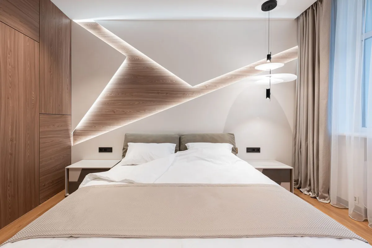 A clean modern bedroom with white linen and indirect lighting, unoccupied