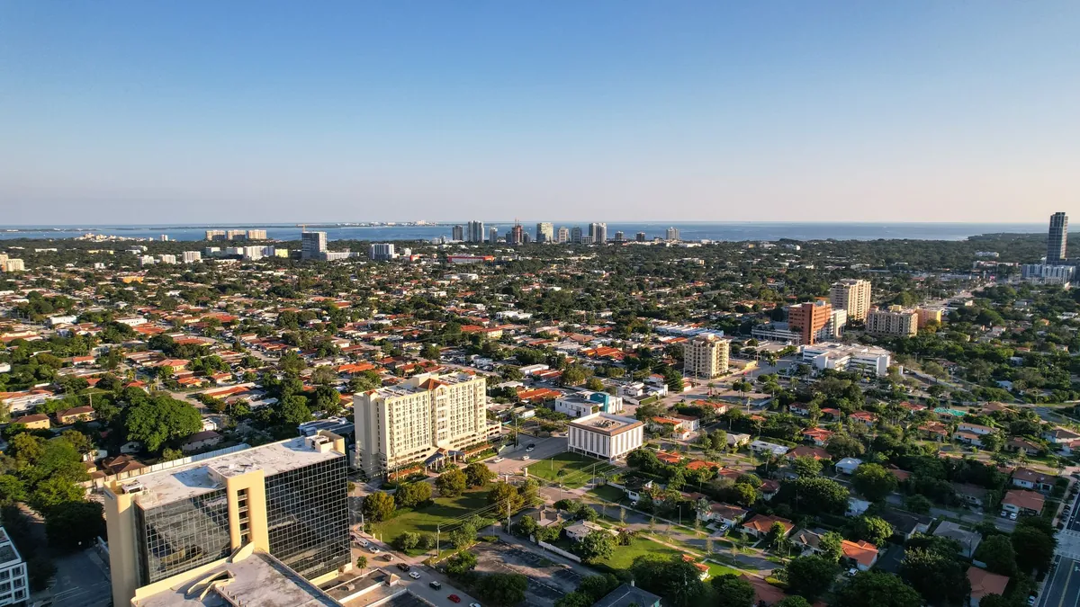An aerial view of a coastal town with low buildings and the sea behind