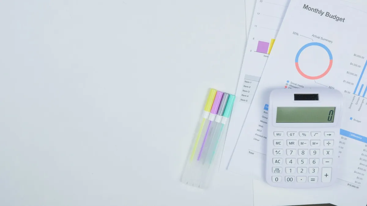 A printed monthly budget sheet with a calculator and coloured tabs