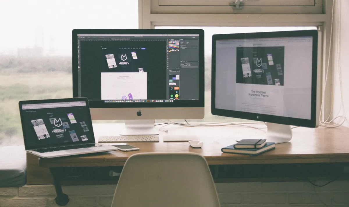 A workspace with a desktop monitor and a laptop showing page layouts side by side