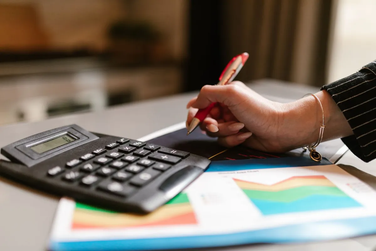 A person using a calculator beside printed charts and documents