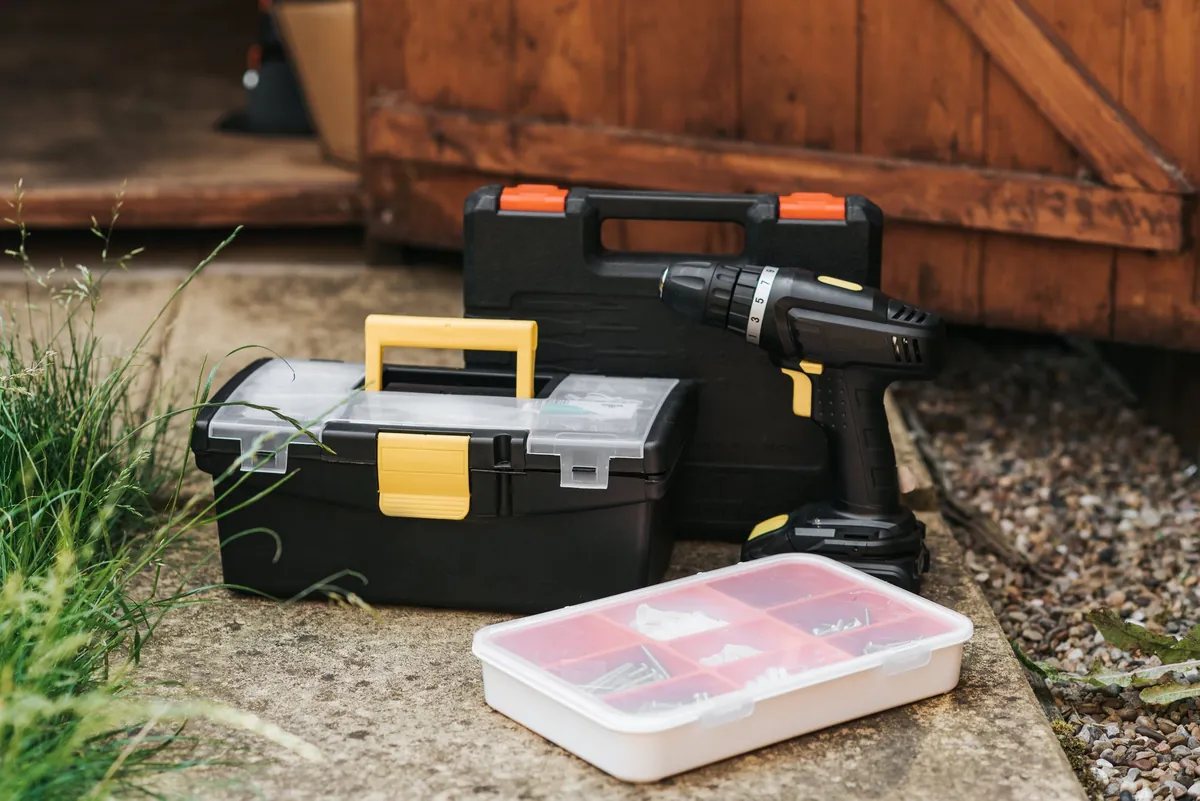 A toolbox and a cordless driver set down by a doorway