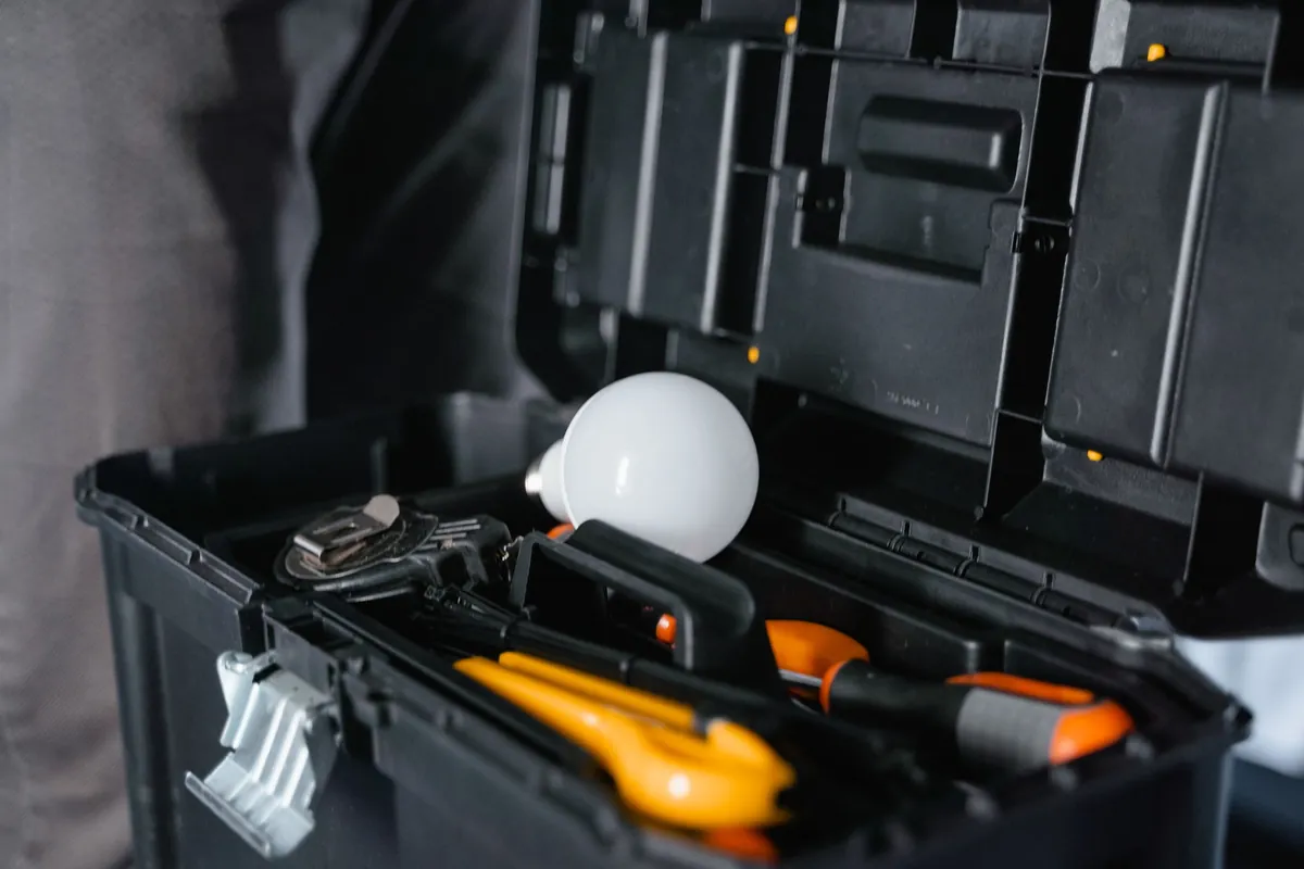 An open toolbox with hand tools and a light bulb inside