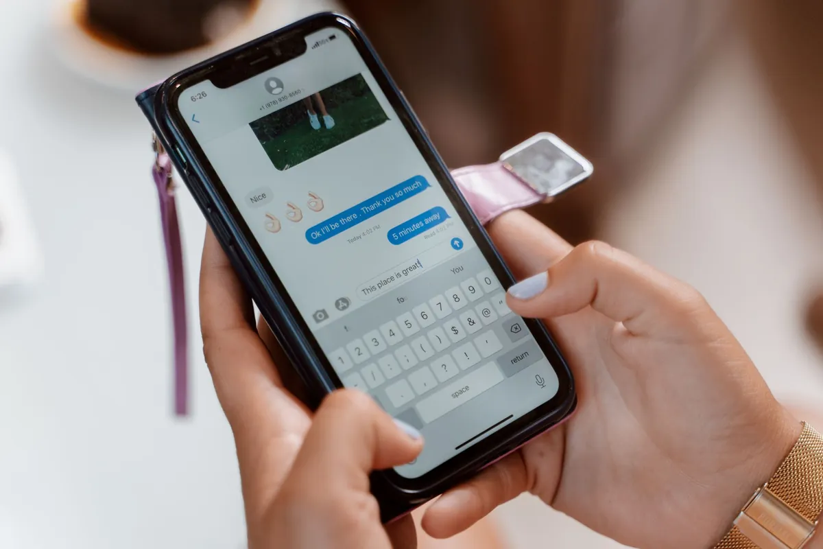 Close-up of two hands typing a message on a phone