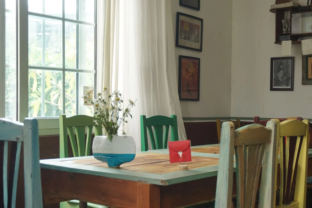 A dining table set with a small card and a vase in a bright rental