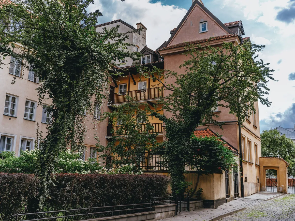 A historic European apartment building on a quiet street, with planting along the pavement