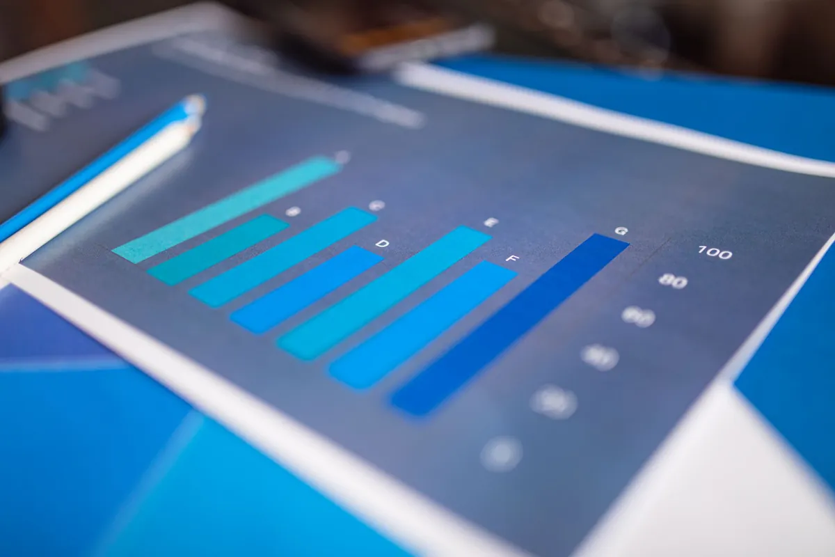 A printed bar chart on a blue background beside a pen