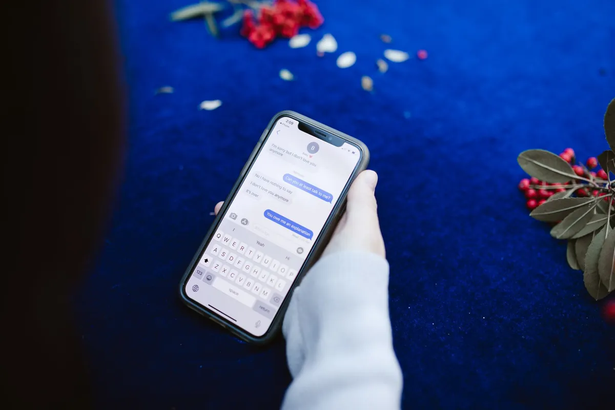 A phone showing a message thread, held over a deep blue surface