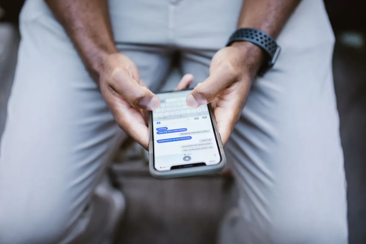 A person sitting with a phone in both hands, reading a conversation