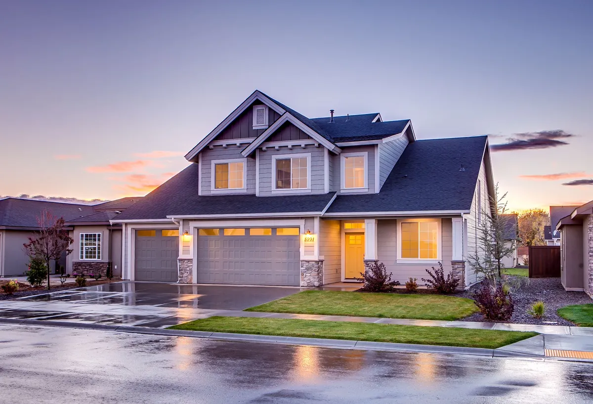 A two-storey suburban house at dusk with warm light in the windows