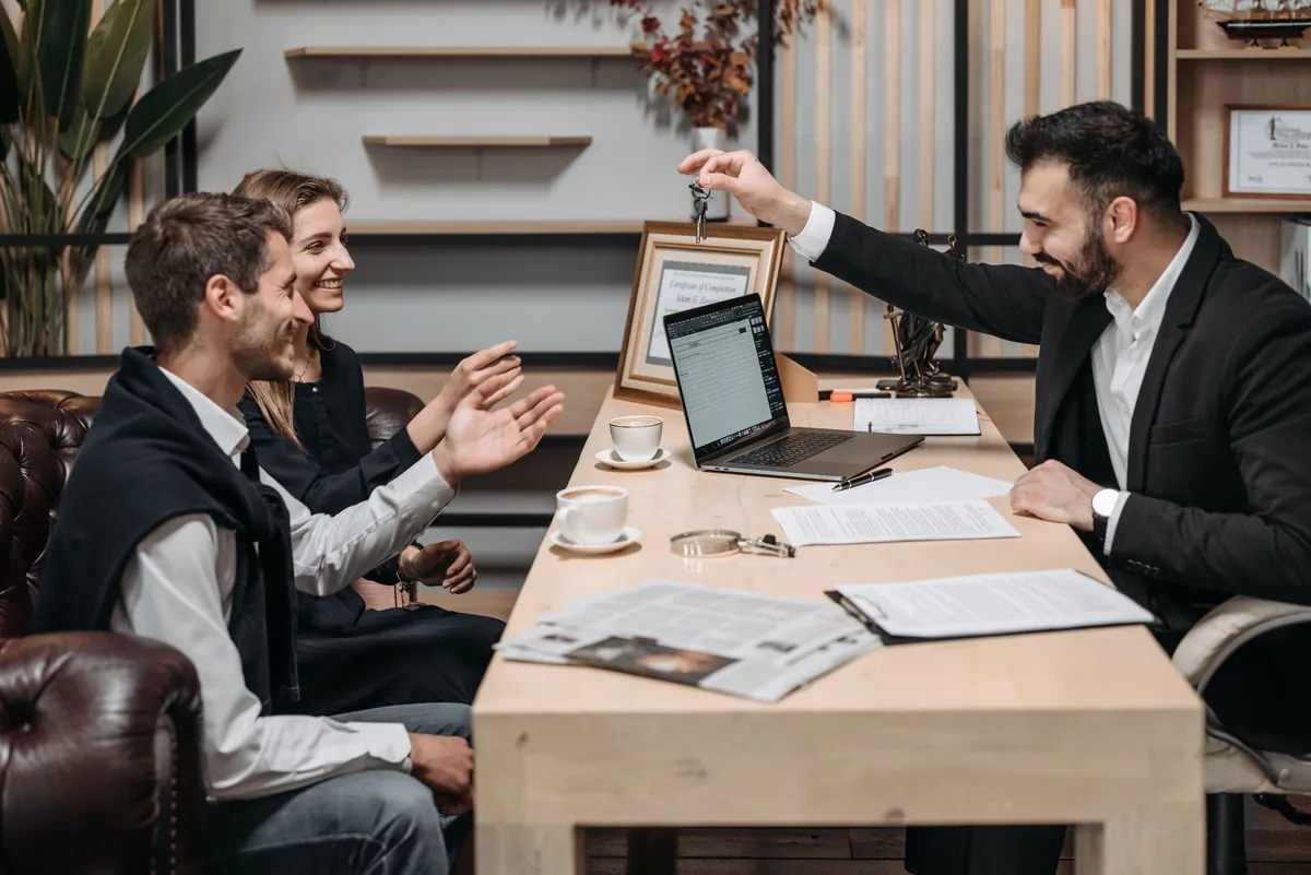 Four people around a table with a laptop, one of them presenting