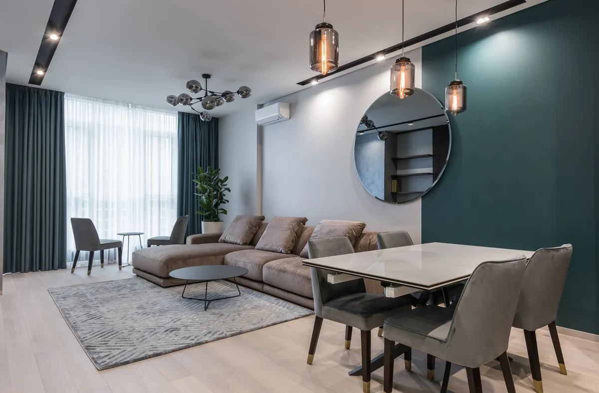 A modern living room with a corner sofa, a dining table and pendant lamps