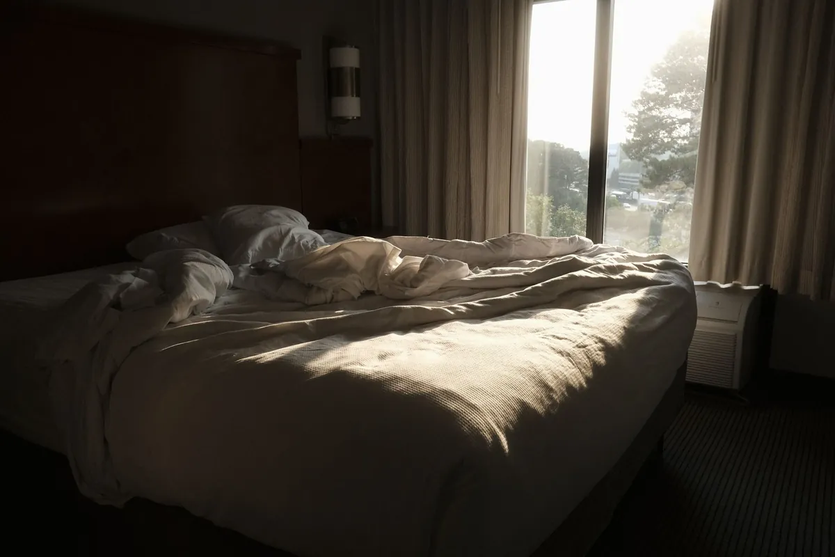 An unmade bed in a bright room in the morning, after a guest has checked out