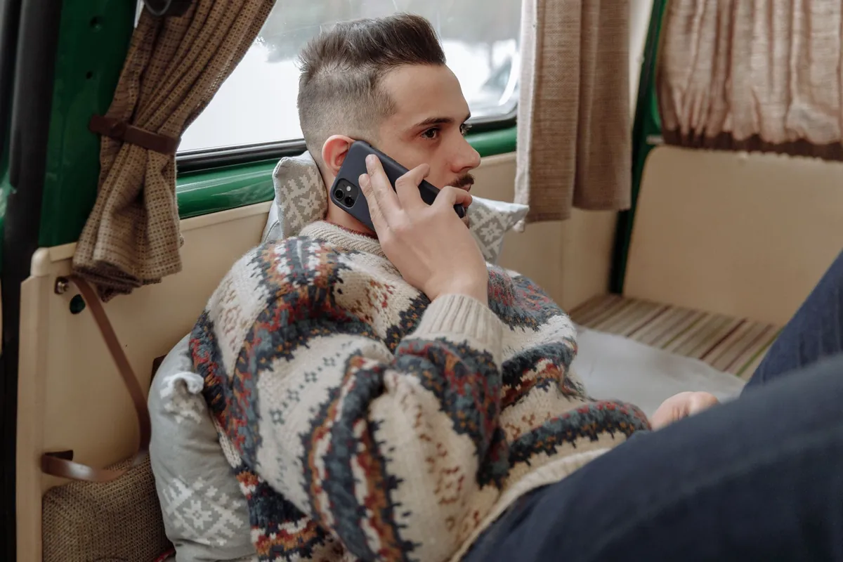 A man on a phone call sitting inside a camper van