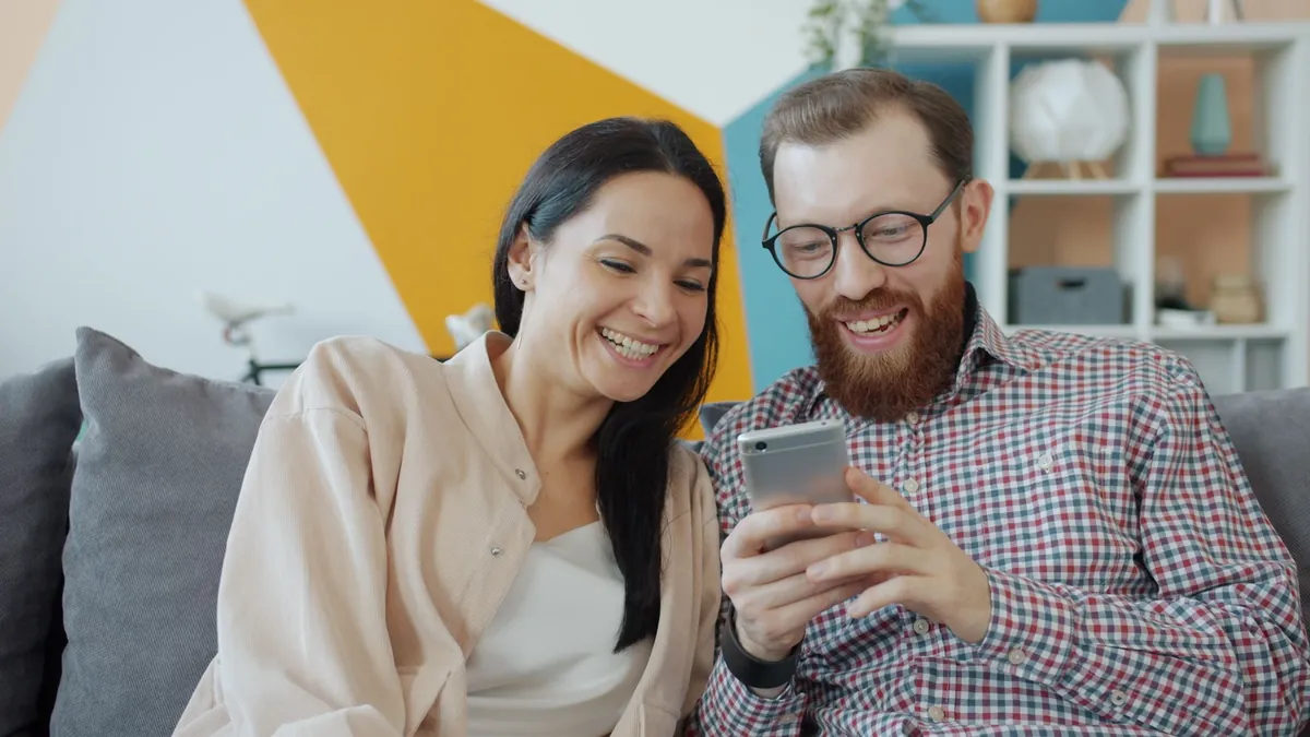 A couple sitting on a sofa looking at a phone together