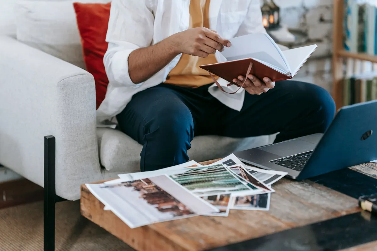 A host sitting with a notebook and a laptop, working through printed material before making a decision