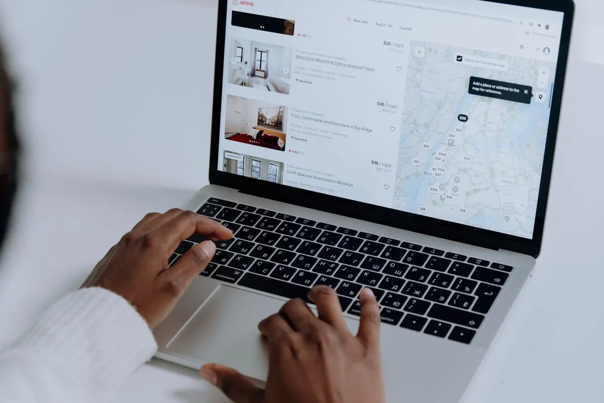 An Airbnb search results page for New York open on a laptop, with listings beside a map